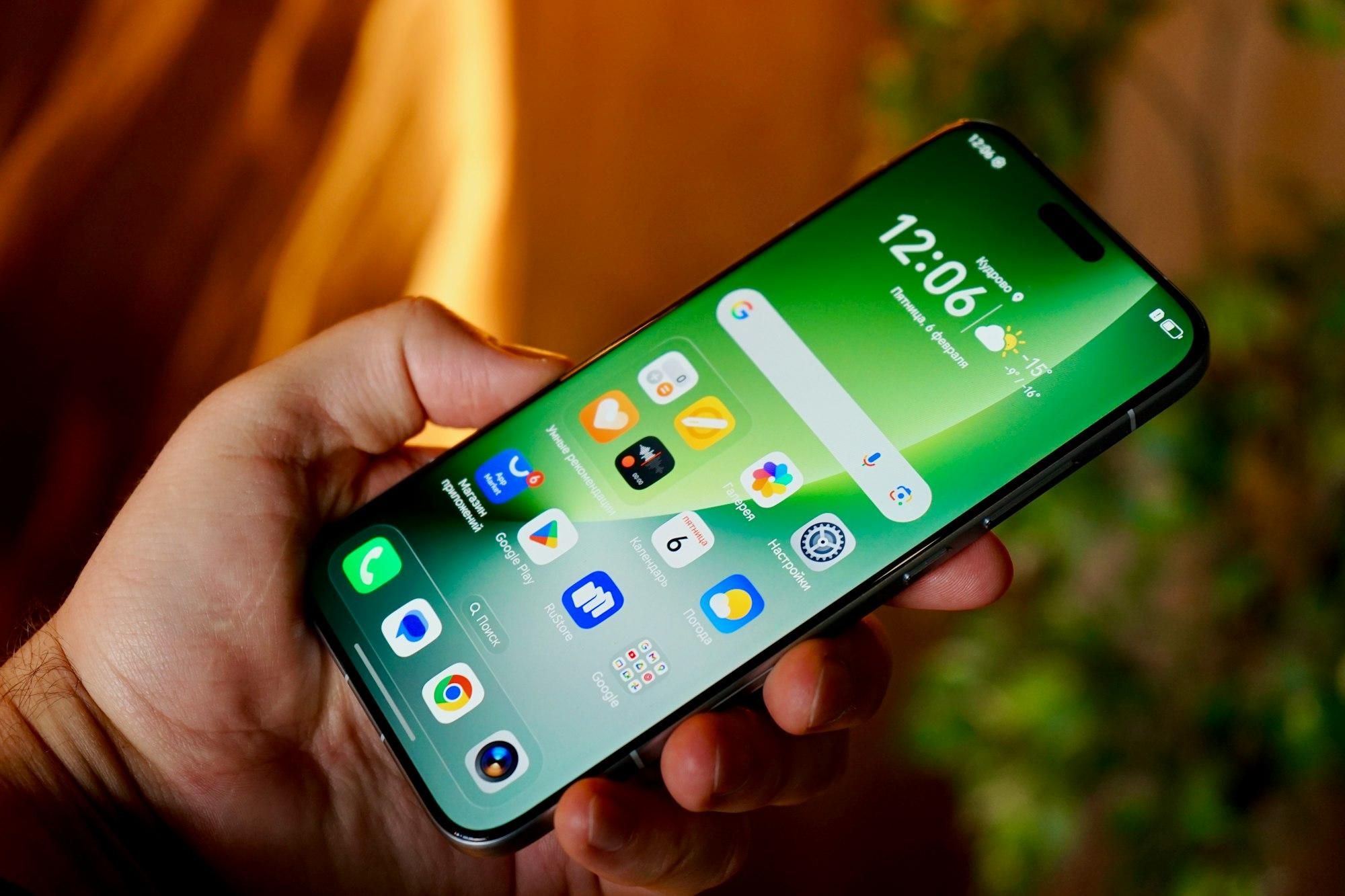 A hand holding an Android smartphone whose home screen shows colorful app icons and the Google search bar