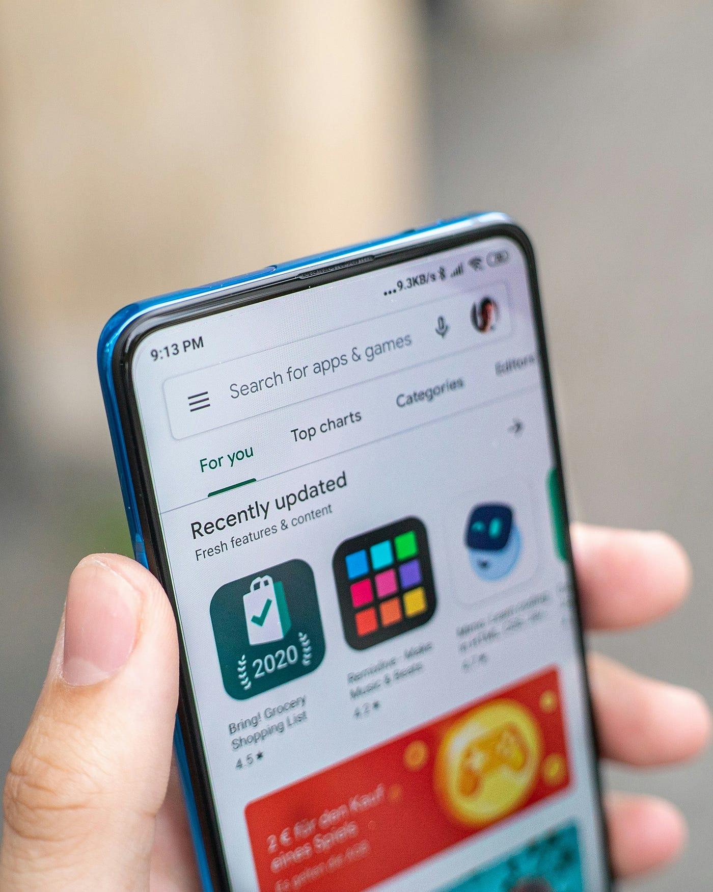 Eine Hand hält ein Smartphone mit geöffnetem Play Store auf der Suche nach Apps